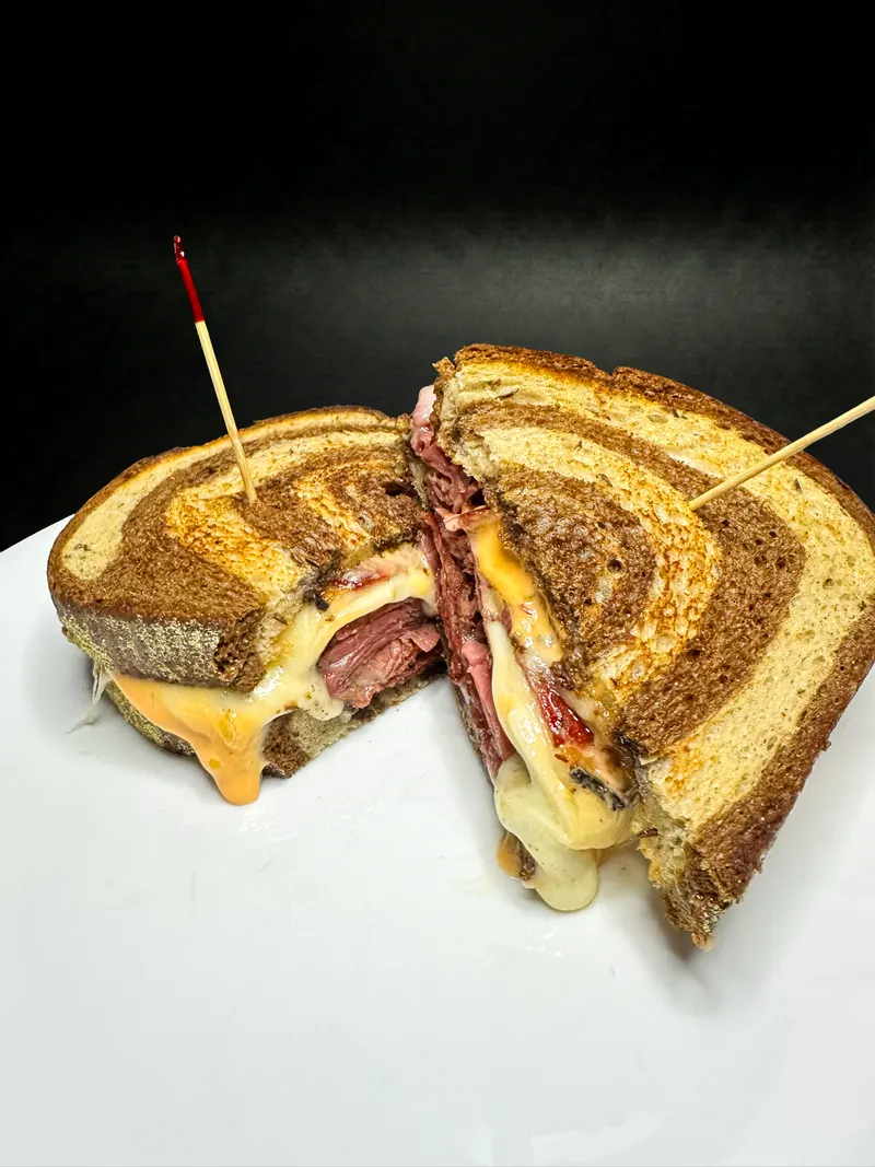 Reuben sandwich close-up showing melted cheese at Macarena's Kitchen